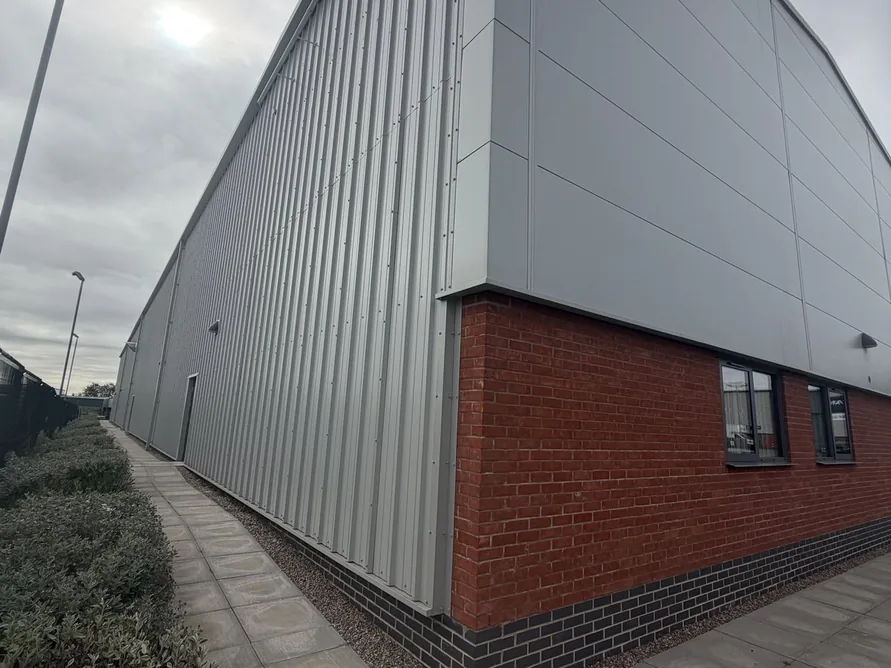 Side elevation of the new unit showing grey cladding and brickwork along the footpath